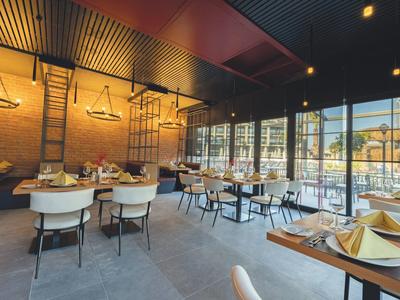 Restaurant moderne avec grandes fenêtres donnant sur une terrasse avec parasols