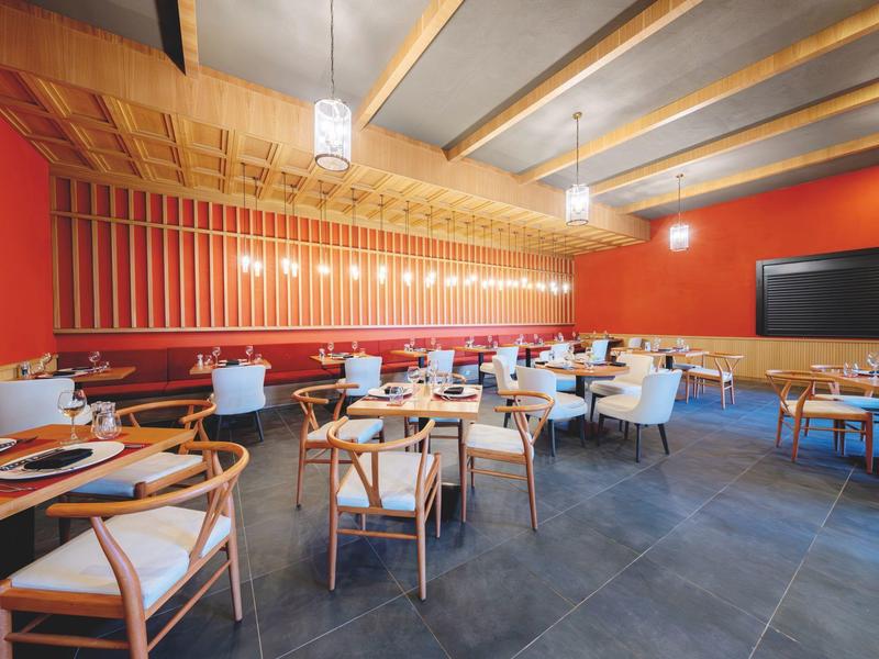 Intérieur de restaurant moderne avec plafond en bois, murs rouge chaud et chaises en bois élégantes.