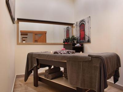 Schlichter Massageraum mit braunem Massagetisch, Handtüchern und dekorativem Bild an der Wand