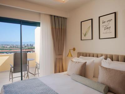 Nowoczesna sypialnia z balkonem, łóżkiem podwójnym, dekoracyjnymi obrazami i widokiem na miasto i morze.