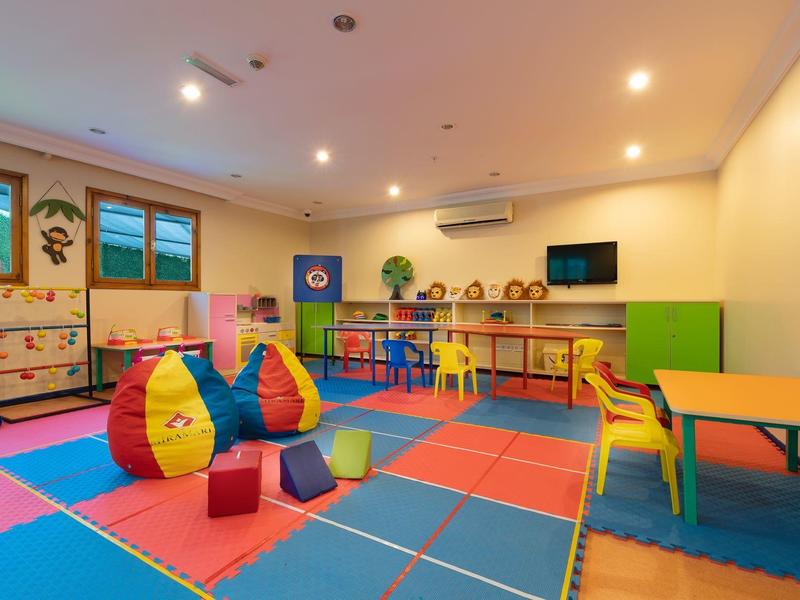 Buntes Spielzimmer mit weichen Sitzsäcken und Tischen in einem Hotel.