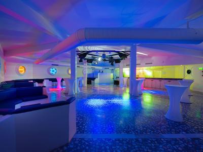 Spazio interno moderno con illuminazione colorata, pista da ballo e area lounge