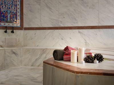 Area benessere con elementi in marmo, candele, asciugamani e uva per il relax