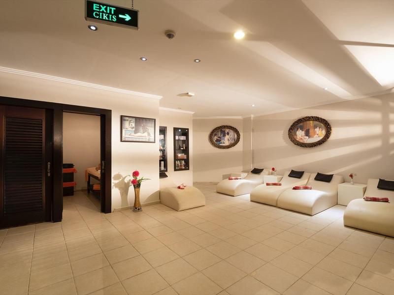 Una sala d'attesa luminosa con poltrone bianche, porte scure e quadri decorativi alle pareti.