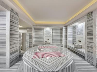 Luxurious marble spa room with round table and towels on striped marble walls and floor.