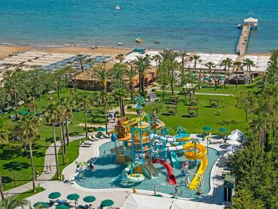 A vibrant water park with slides and pools near a sandy beach and ocean pier.