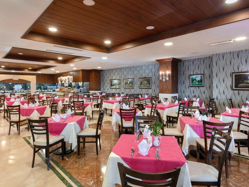 Large restaurant with wooden ceiling, pink and white tablecloths, and dark wooden chairs.