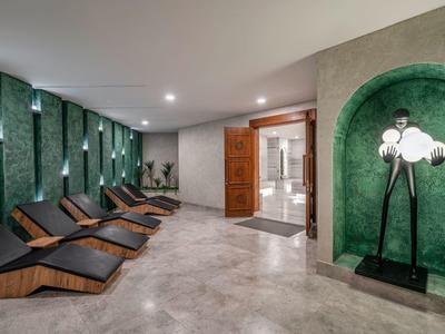 Espace détente moderne avec murs verts et chaises longues confortables dans un spa d'hôtel.