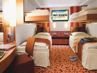 Chambre d'hôtel avec deux lits superposés, moquette et bureau avec lampe.