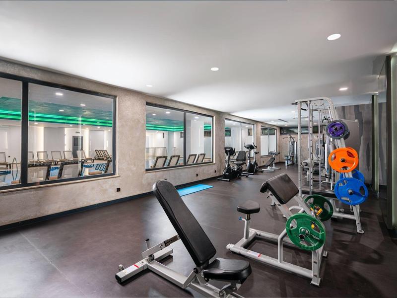 Salle de sport moderne avec équipements et vue sur une piscine intérieure lumineuse.