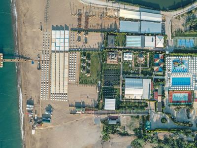 Luchtfoto van een strandresort met zwembaden, parasols en directe toegang tot het strand.