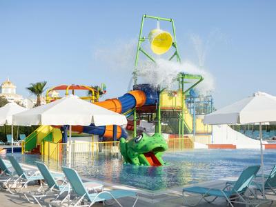 Glijbaan en ligstoelen op een zonnige dag in het waterpark van een hotel.