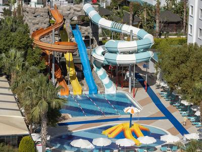Meerdere kleurrijke glijbanen in een hotel-waterpark met ligstoelen en bomen.