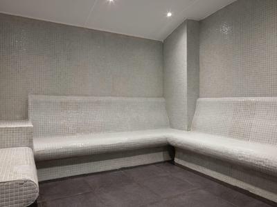 Moderne wellnessruimte met beklede mozaïekbanken en grijze muren.