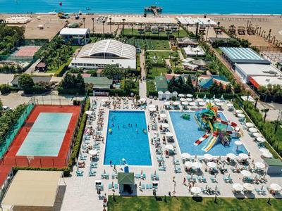 Hotelcomplex met meerdere zwembaden, waterspeeltuin en tennisbaan dicht bij het strand.