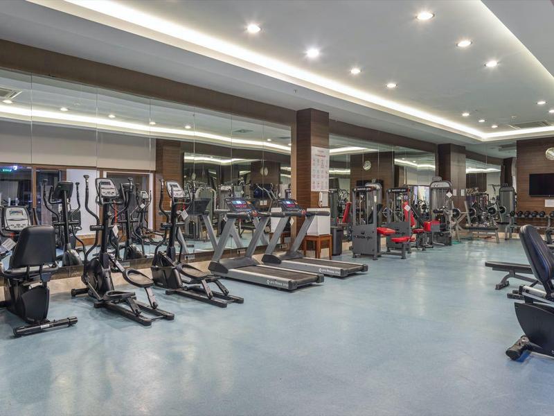 Ruime fitnessruimte met moderne apparatuur en heldere plafondverlichting.