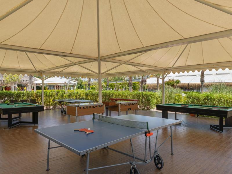 Overdekte recreatieruimte met tafeltennis- en biljarttafels bij een hotel.