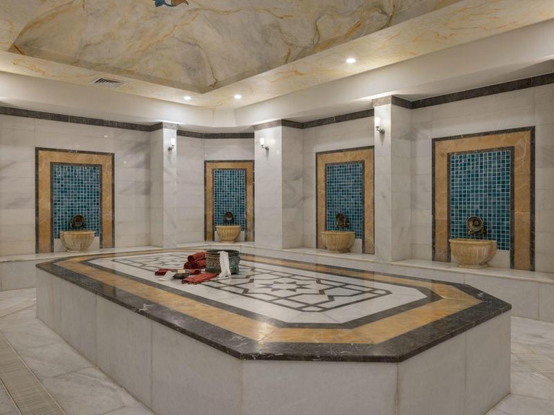 Elegante hammam met marmeren muren en artistieke waterbakken, perfect voor ontspanning.