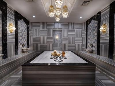 Luxe spakamer met een centrale massagetafel en elegante verlichtingsarmaturen.