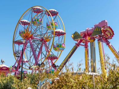 Kleurrijk reuzenrad en attractie onder blauwe hemel in een pretpark