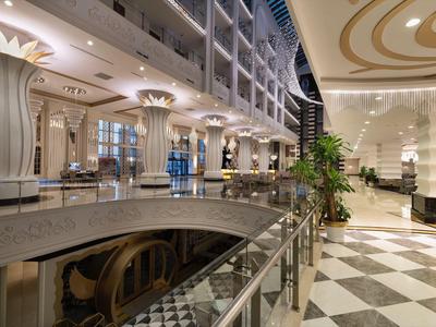 Moderne hotelhal met marmeren vloer, zuilen en glazen balustrade verlicht in de nacht