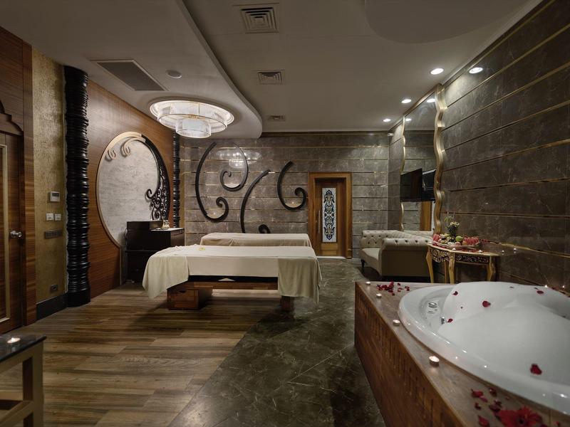 Luxe hotelkamer met groot bed, elegante kroonluchter en ruime jacuzzi.