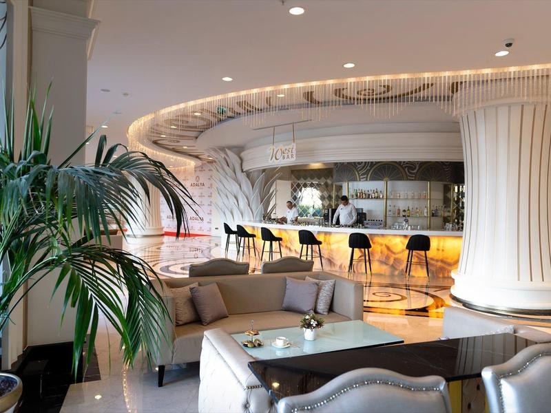 Elegante hotel lounge met gebogen bar, comfortabele zitplaatsen, warme verlichting en sierplanten.