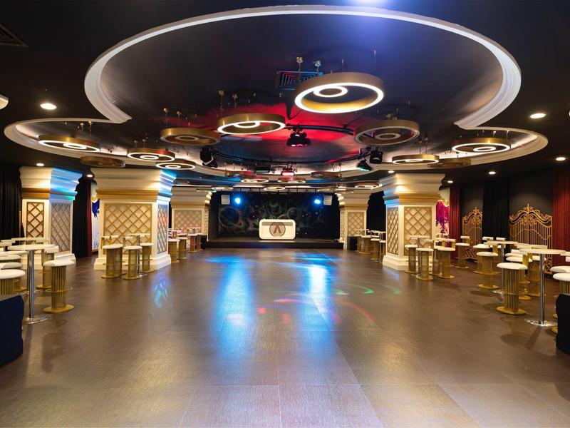 Velká moderní taneční místnost s dekorativním osvětlením a stoly kolem tanečního parketu.