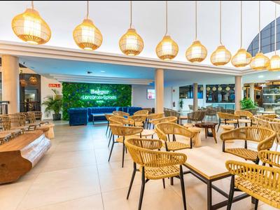 Helles Restaurant mit modernen Bambusstühlen und hängenden Lampen in einem Hotel.