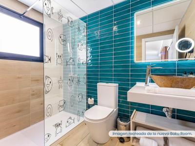 Moderní koupelna s modrými dlaždicemi, sprchou, toaletou a umyvadlem se zrcadlem.