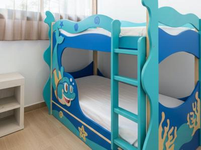 Kinderhochbett in blau mit Meeresmotiven und Leiter neben einem kleinen weißen Regal.