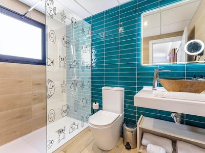 Modernes Badezimmer mit blauen Wandfliesen, Glasduschwand und Holzwaschbecken.