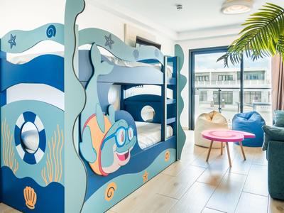Kinderzimmer mit maritimem Etagenbett und hellem Wohnzimmerbereich in einem Hotel.