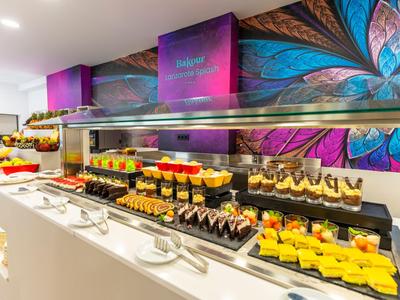 Buntes Dessertbuffet mit verschiedenen Kuchen und Schichten in einem modernen Hotel.