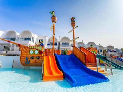 Hellblauer Himmel über einem Spielplatz mit bunten Rutschbahnen auf einem Holzschiff.
