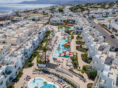 Luftaufnahme eines Resorts mit Pools und weißen Gebäuden an der Küste.