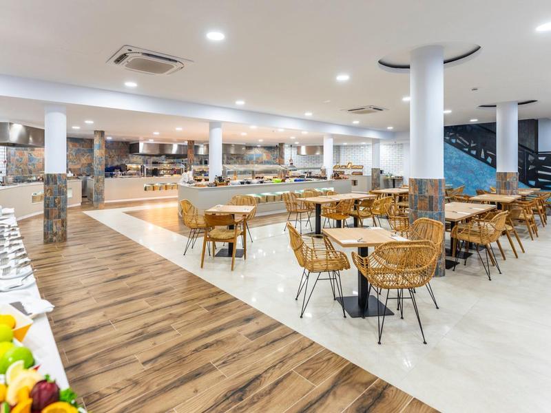 Großes, modernes Restaurant mit Holz- und Metallstühlen, Buffetbereich und hellem Boden.