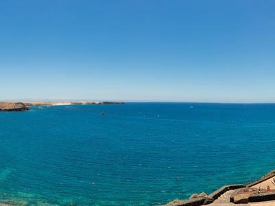 Mer bleue claire avec côte rocheuse sous un ciel clair.