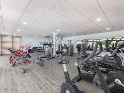 Moderner Fitnessraum mit Cardiogeräten und Kraftstationen in einem Hotel.