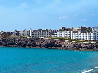 Grand complexe hôtelier sur une côte rocheuse avec mer bleu vif