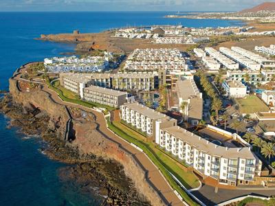 Complexe hôtelier sur une falaise avec vue sur la mer et le paysage côtier environnant.
