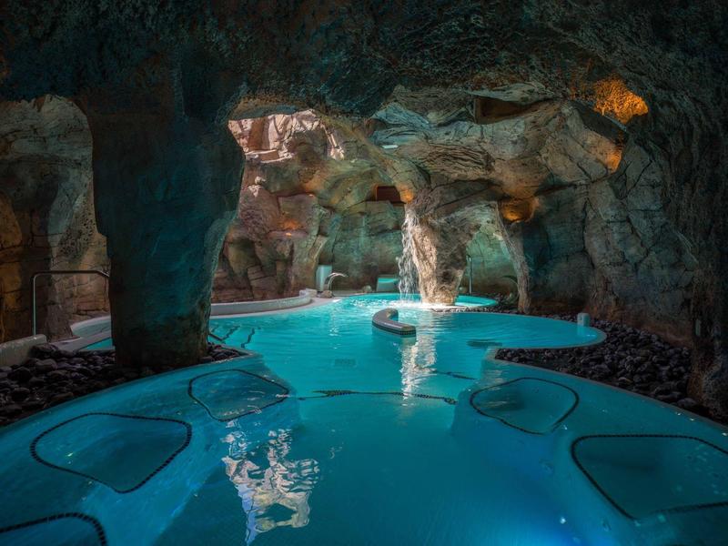 Piscine intérieure dans un cadre naturel de type grotte avec eau bleue et formations rocheuses