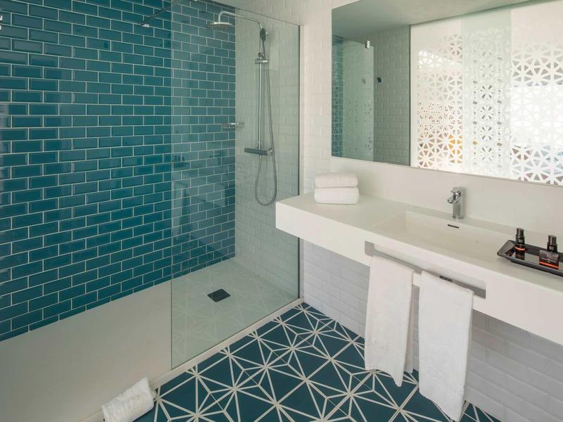 Modern bathroom with blue tiled shower and white sink.