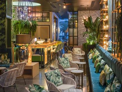 Modern eingerichteter Hotel-Loungebereich mit Sitzgelegenheiten, Pflanzen und gedämpfter Beleuchtung.