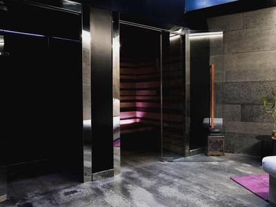 Moderner Wellnessbereich mit Sauna, grauen Fliesen, dunklen Wänden und lila Beleuchtung.