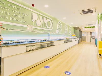 Buffet moderno y luminoso en un hotel con una larga barra y señalización clara en la pared.