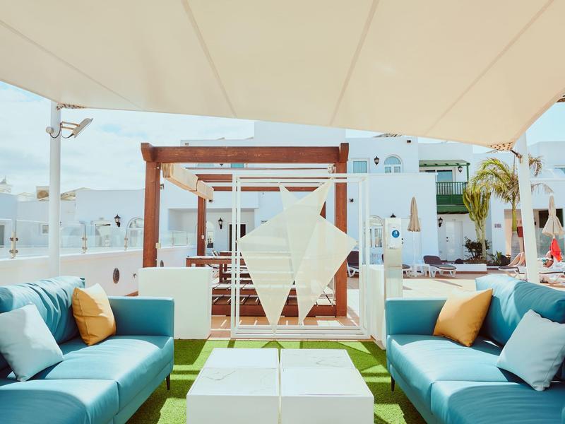 Lounge moderna con sofás y sombra en una zona exterior luminosa y relajada.