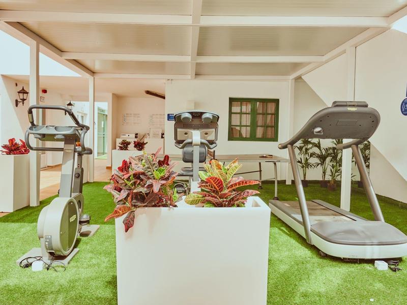 Zona de fitness con cinta de correr y bicicleta en césped artificial interior.