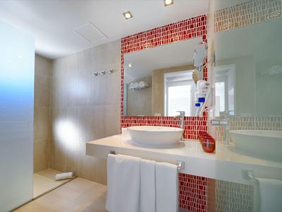 Modernes Badezimmer mit Waschbecken, großem Spiegel und roten Fliesen.