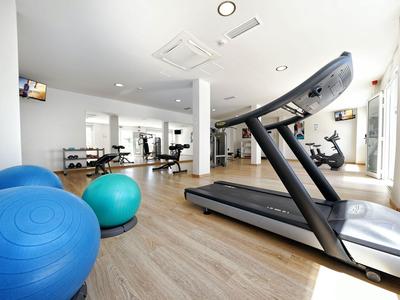 Helles Fitnessstudio mit Laufband, Gymnastikbällen und weiterem Trainingsgerät.